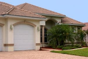 a generic one story florida home with garage, palm trees and a clear blue sky